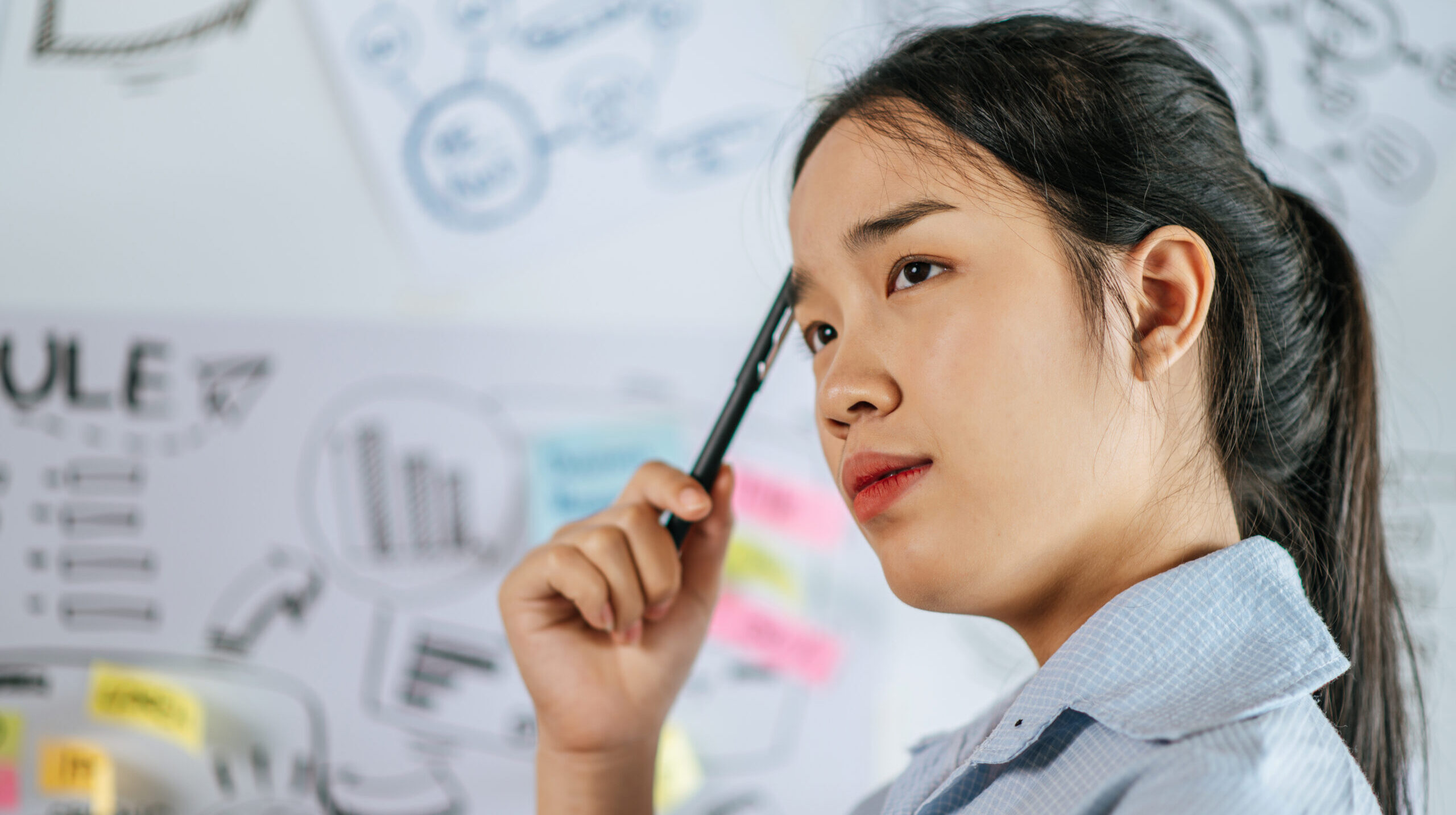Young asian woman standing and thoughtful how to present planing of project on board in meeting room, copy space